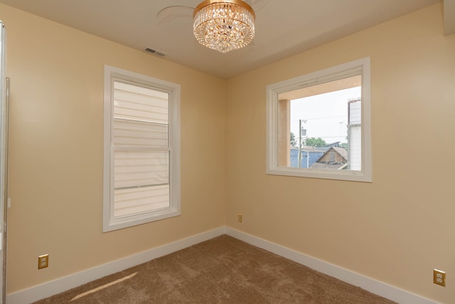 carpeted spare room featuring a notable chandelier