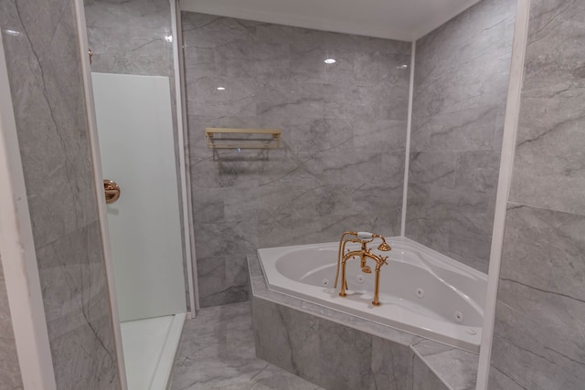 bathroom with tile walls, tile flooring, and tiled tub