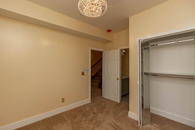 unfurnished bedroom with an inviting chandelier, light carpet, and a closet