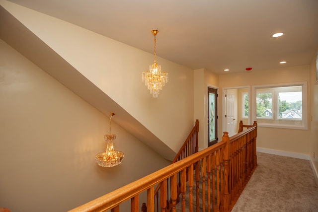 corridor with a chandelier and dark carpet