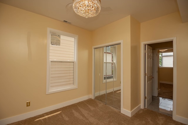 unfurnished bedroom with dark colored carpet, a closet, and a chandelier