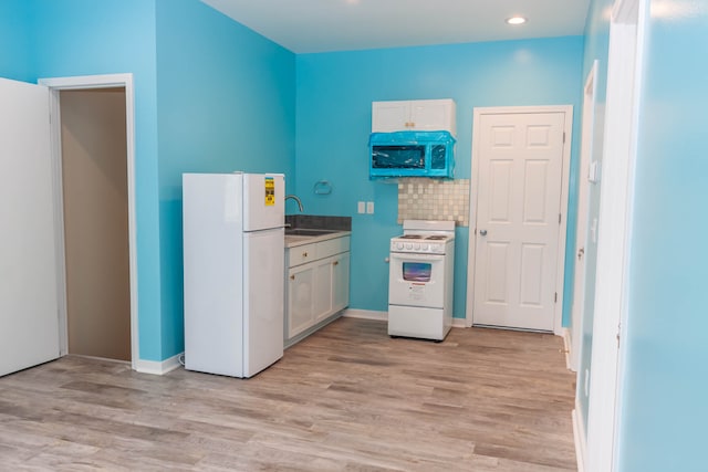 kitchen with white appliances, sink, light wood-type flooring, and white cabinetry