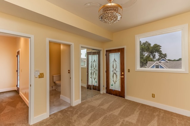 carpeted foyer featuring an inviting chandelier