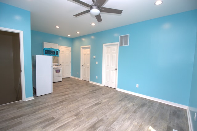 unfurnished bedroom with ceiling fan, white fridge, and hardwood / wood-style floors