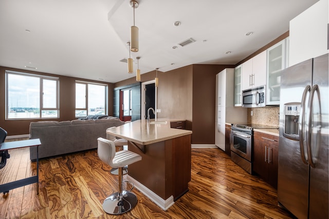 kitchen with dark hardwood / wood-style floors, backsplash, stainless steel appliances, decorative light fixtures, and white cabinetry