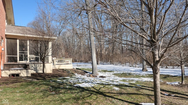 yard covered in snow featuring a sunroom and a deck