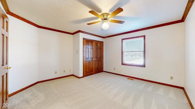 unfurnished bedroom featuring crown molding, light colored carpet, and ceiling fan