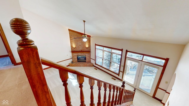 stairs featuring ceiling fan, carpet flooring, a fireplace, and vaulted ceiling