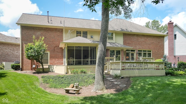 back of property featuring a wooden deck, a sunroom, and a lawn