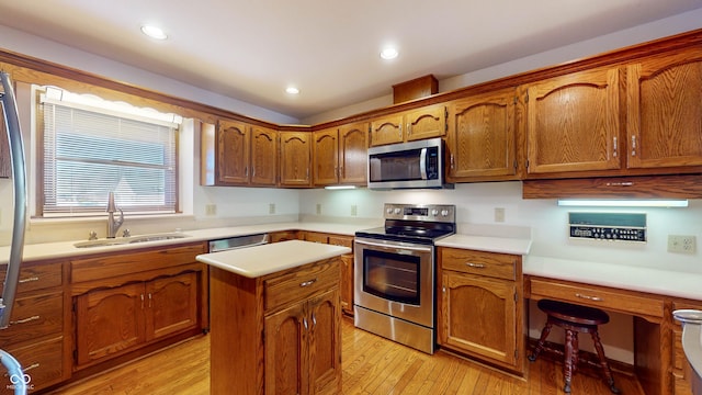 kitchen featuring sink, stainless steel appliances, a center island, and light wood-type flooring