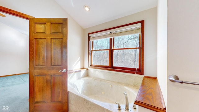 bathroom featuring a relaxing tiled tub and lofted ceiling