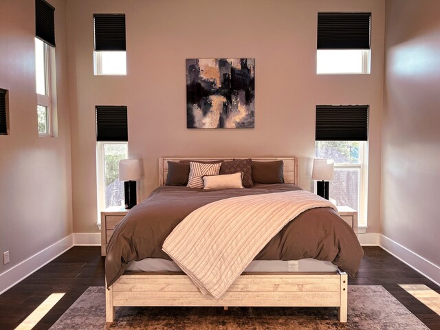 bedroom with a high ceiling and dark hardwood / wood-style floors