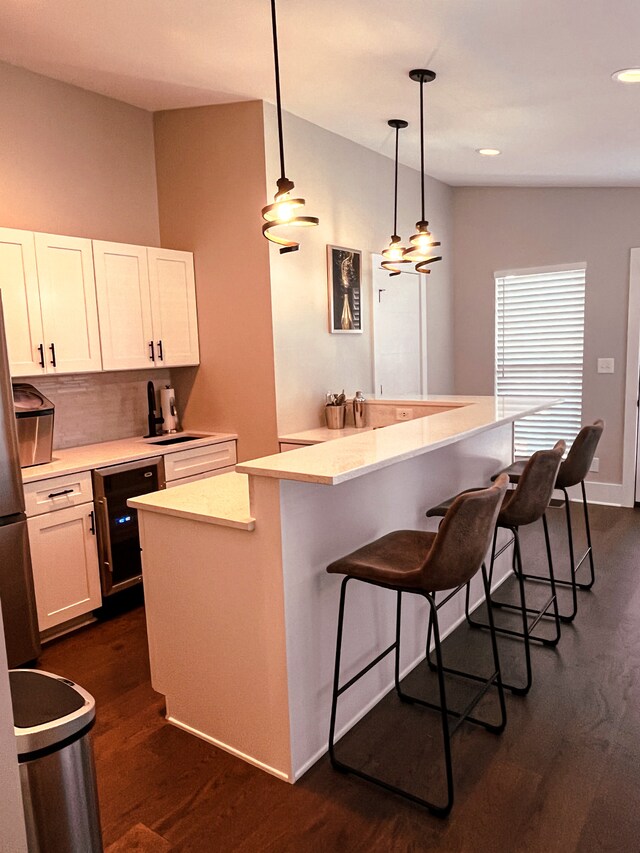 kitchen featuring pendant lighting, a kitchen island, a breakfast bar, white cabinets, and dark hardwood / wood-style flooring