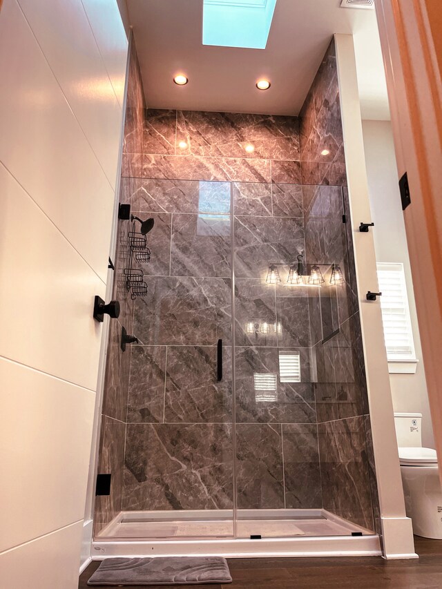 bathroom with an enclosed shower, a skylight, and toilet