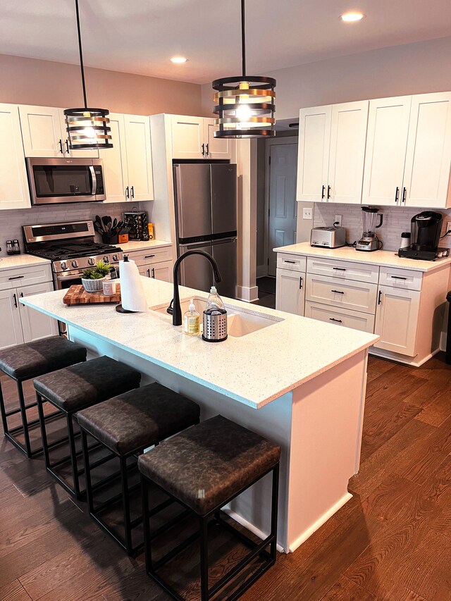 kitchen featuring pendant lighting, stainless steel appliances, backsplash, and dark wood-type flooring