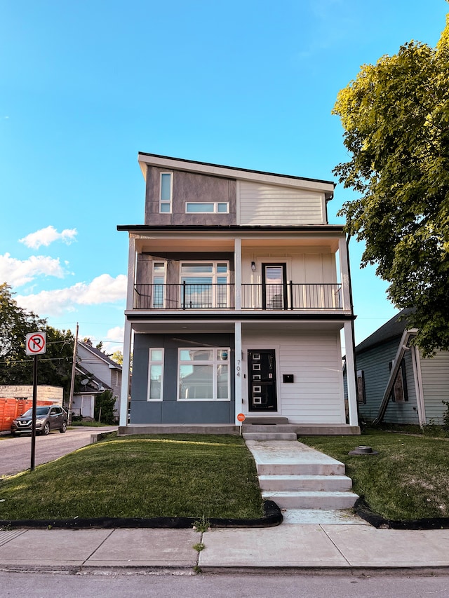 view of front of house with a front lawn and a balcony