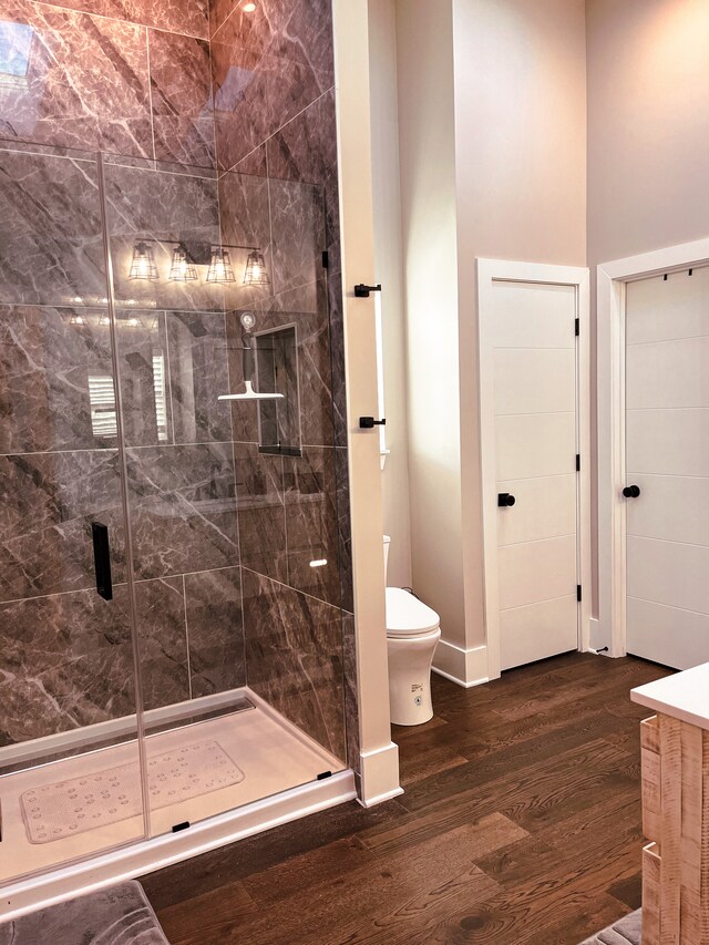 bathroom featuring vanity, toilet, a shower with shower door, and hardwood / wood-style flooring