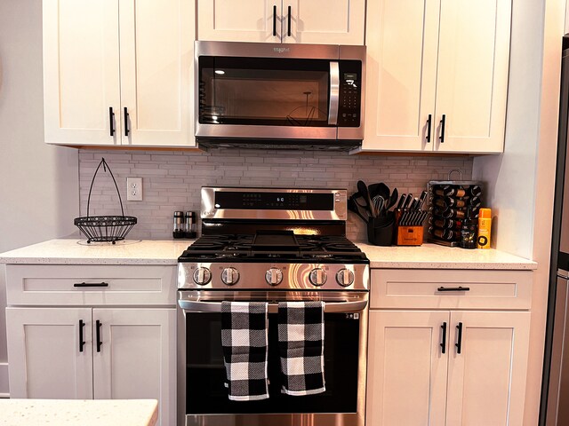 kitchen with white cabinetry, backsplash, light stone counters, and stainless steel appliances