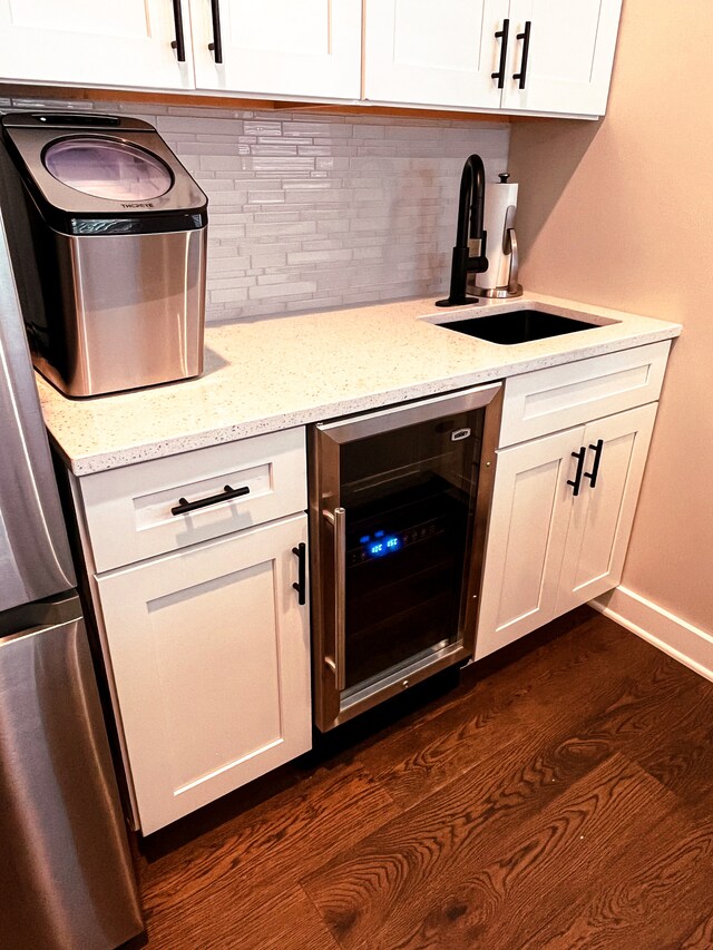 kitchen featuring beverage cooler, tasteful backsplash, dark wood-type flooring, white cabinets, and light stone counters