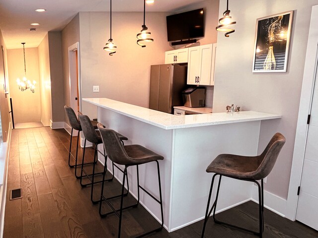 bar with dark hardwood / wood-style flooring, white cabinets, a chandelier, stainless steel refrigerator, and decorative light fixtures