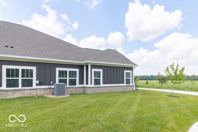 back of property with central air condition unit and a lawn