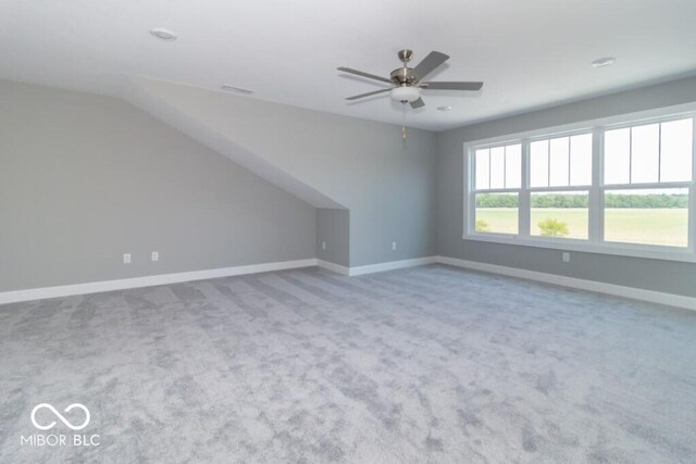 carpeted spare room with ceiling fan and vaulted ceiling