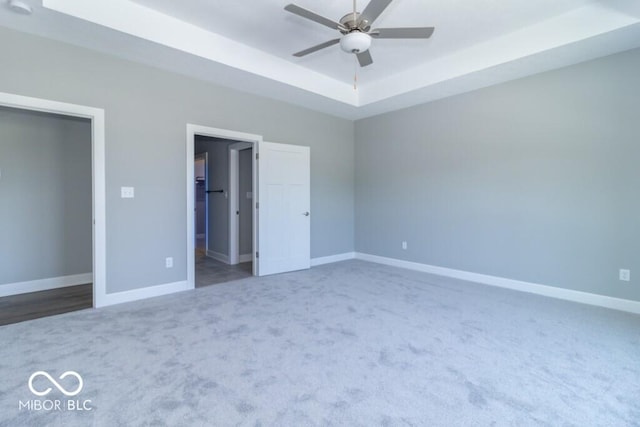 unfurnished bedroom featuring a raised ceiling, carpet floors, and ceiling fan