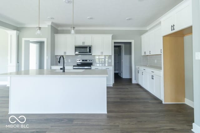 kitchen featuring stainless steel appliances, decorative light fixtures, an island with sink, and white cabinets