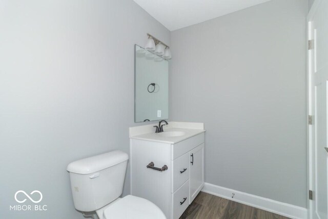 bathroom featuring toilet, vanity, and hardwood / wood-style flooring