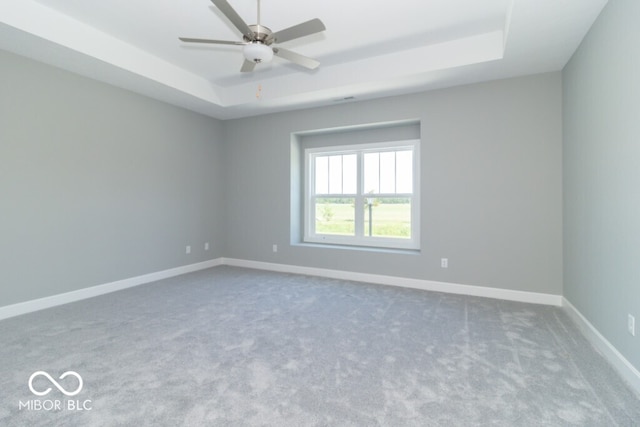 unfurnished room with a tray ceiling, carpet flooring, and ceiling fan