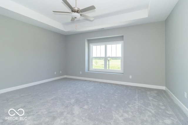 spare room with ceiling fan, a raised ceiling, and carpet floors