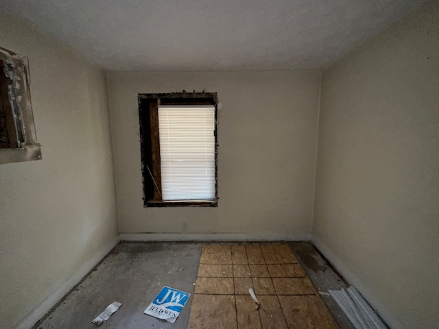 tiled empty room with a textured ceiling