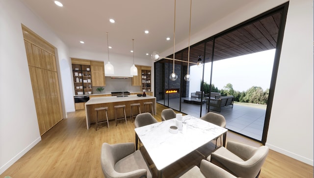 dining area with floor to ceiling windows, light wood-type flooring, and a fireplace