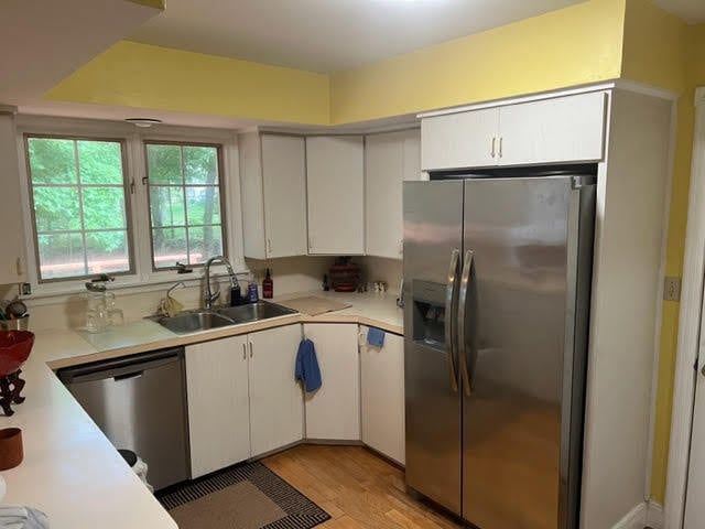 kitchen with sink, stainless steel appliances, light wood-type flooring, and white cabinetry