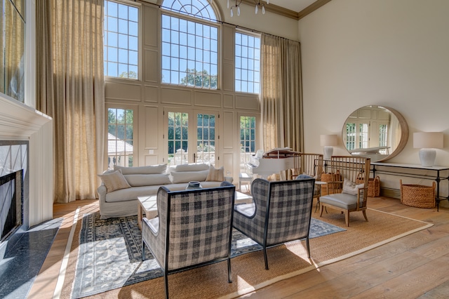 living room with a fireplace, light wood-type flooring, and a towering ceiling