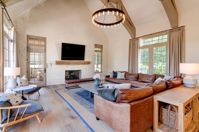 living room with a fireplace, light hardwood / wood-style flooring, a chandelier, and high vaulted ceiling