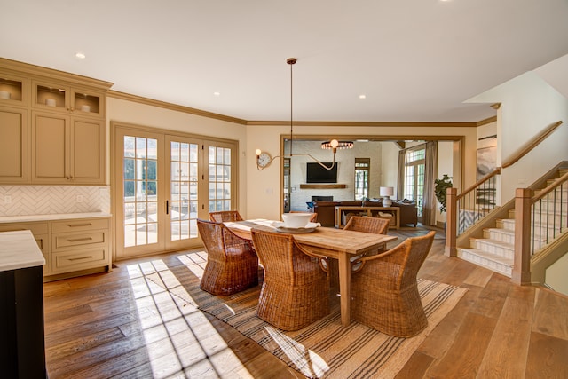 dining space with french doors, ornamental molding, and light hardwood / wood-style flooring