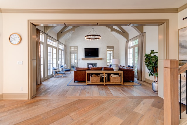 interior space featuring an inviting chandelier, lofted ceiling with beams, light wood-type flooring, and a fireplace