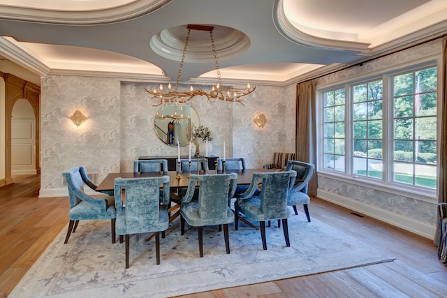 dining area with a chandelier, light hardwood / wood-style floors, a healthy amount of sunlight, and a tray ceiling