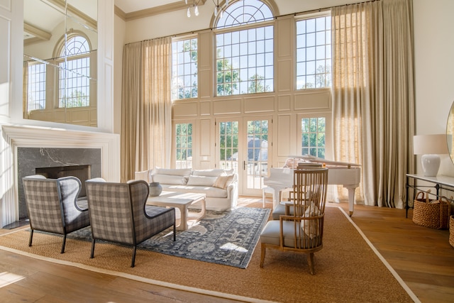 living room with a high end fireplace, light wood-type flooring, and a high ceiling