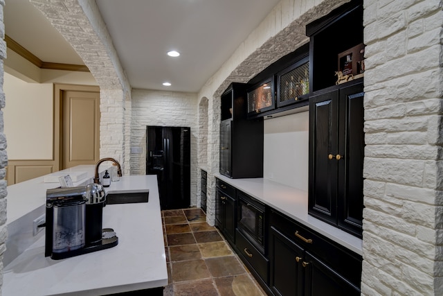 kitchen with dark tile flooring, ornamental molding, black appliances, and sink