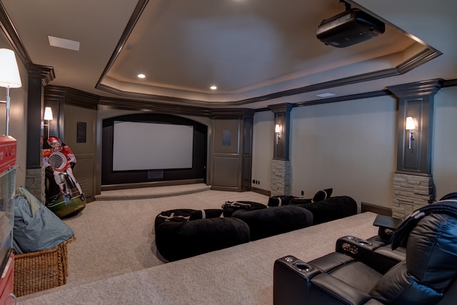 carpeted cinema room with crown molding, a tray ceiling, and ornate columns