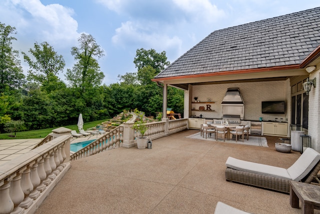 view of patio with exterior kitchen, a fireplace, and grilling area