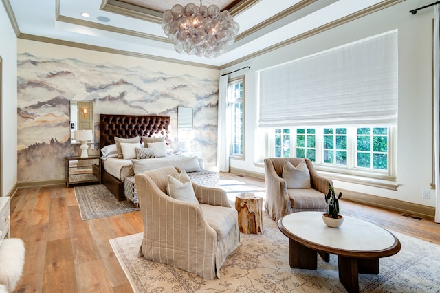 bedroom featuring an inviting chandelier, crown molding, light wood-type flooring, and a raised ceiling