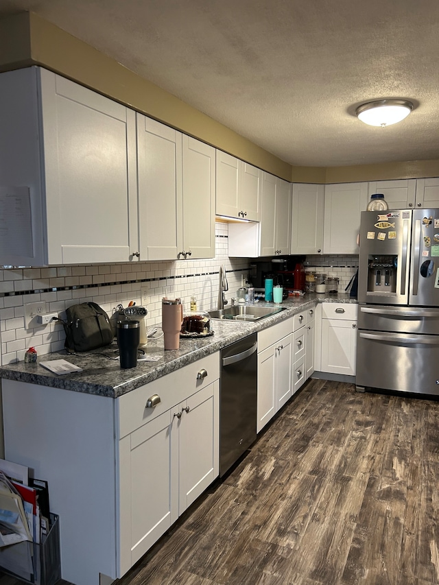 kitchen featuring stainless steel appliances, dark wood-type flooring, white cabinetry, backsplash, and sink