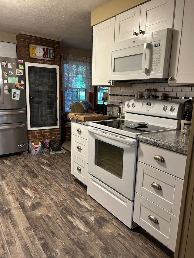 kitchen with dark stone counters, white appliances, a textured ceiling, white cabinetry, and dark hardwood / wood-style floors