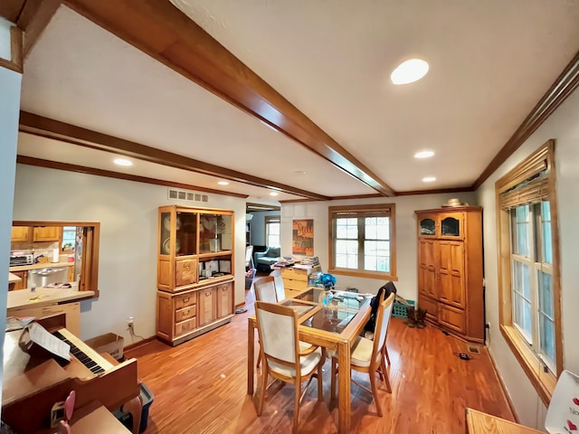 dining room with beam ceiling, light hardwood / wood-style flooring, and crown molding