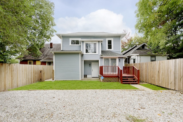 rear view of house with a wooden deck and a lawn