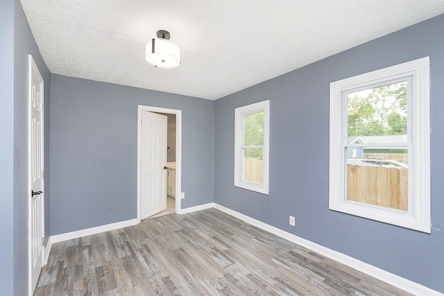 unfurnished room with plenty of natural light, hardwood / wood-style floors, and a textured ceiling