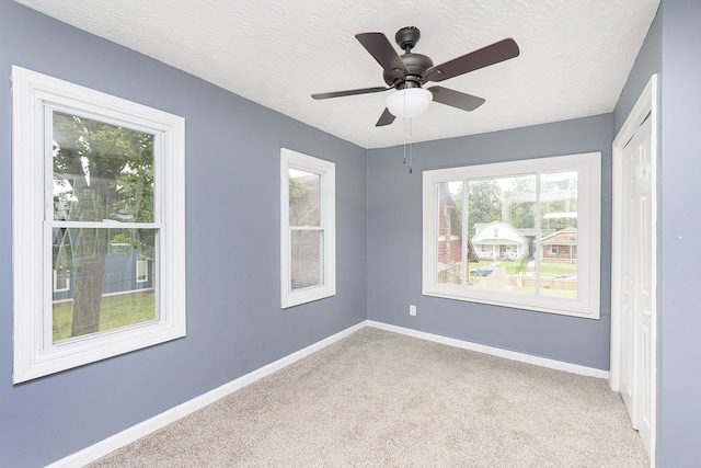 spare room with light carpet, ceiling fan, and a textured ceiling